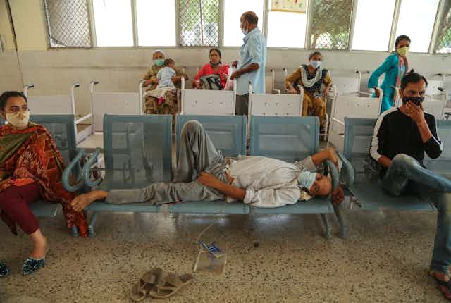 Indian man in mask lying on chairs in hospital. 