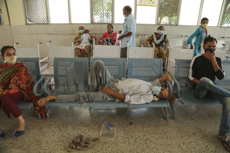 Indian man in mask lying on chairs in hospital.