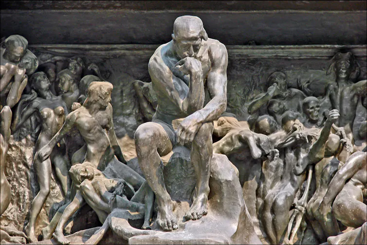 Statue of man thinking surrounded by an orgy of other people.