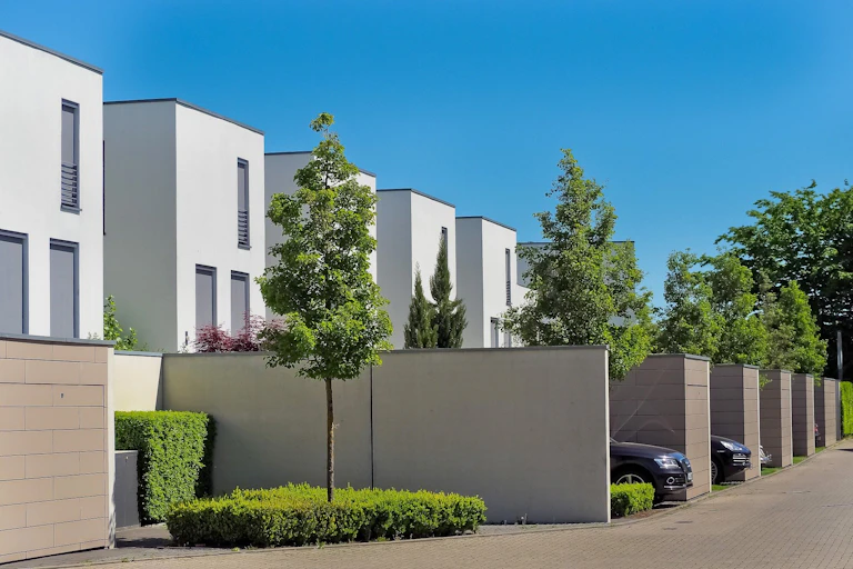 Rows of identical white houses with cars and trees outside