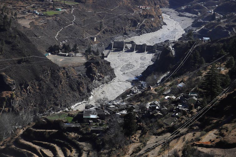 Aerial view of a damaged dam in a mountain valley.
