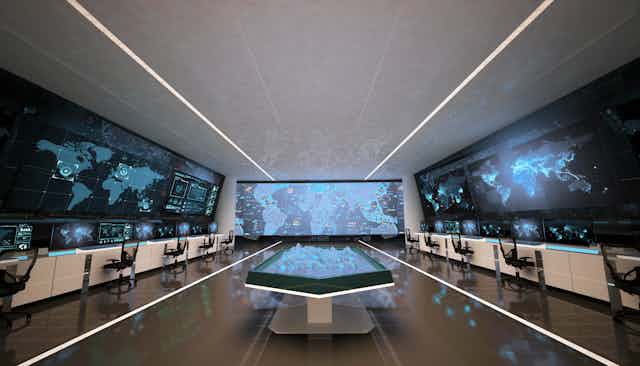 An empty control room with three large screens and a holographic table