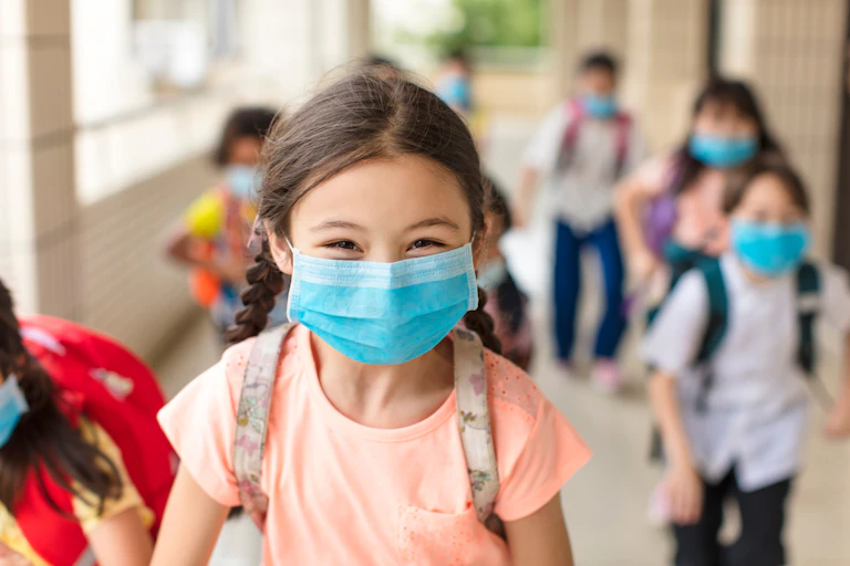 Alumnos de colegio con mascarillas, con una niña sonriente en primer plano.