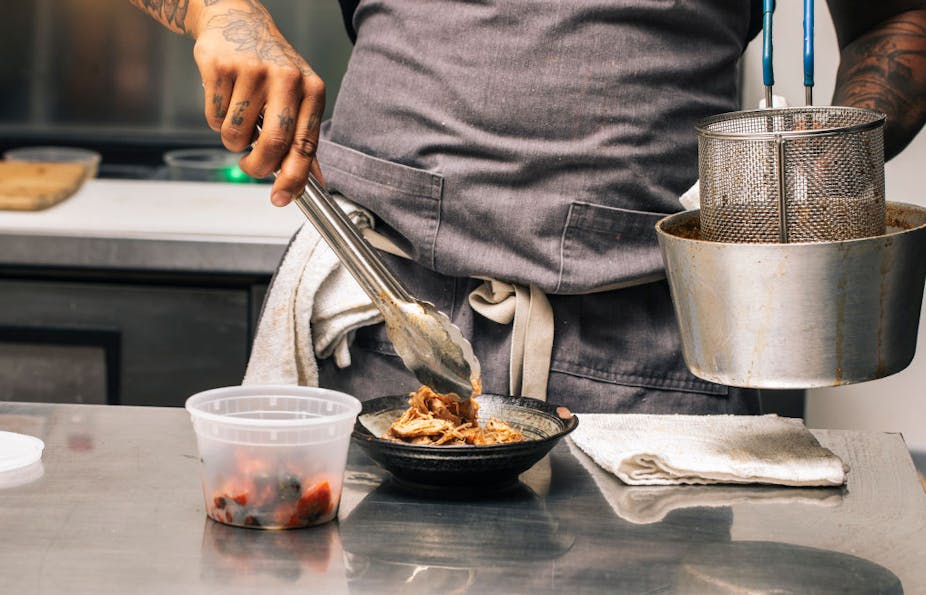 Man puts food in a bowl using tongs.