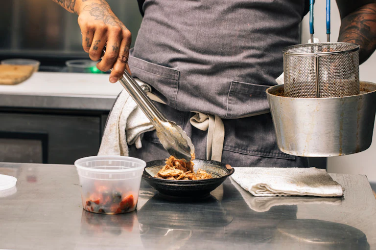 Man puts food in a bowl using tongs.