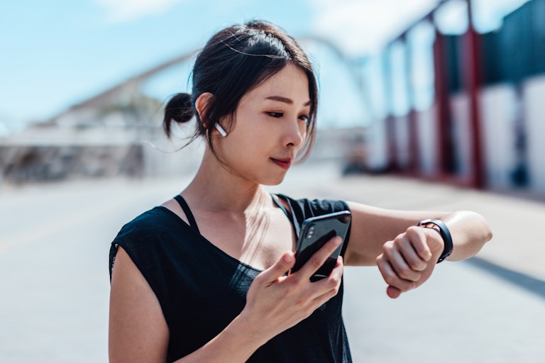 Young woman using smartwatch and doing outdoor workout in the city