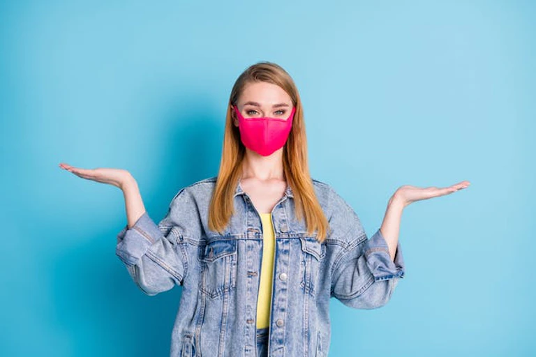Wanita muda mengenakan topeng dengan tangan di udara, ragu-ragu