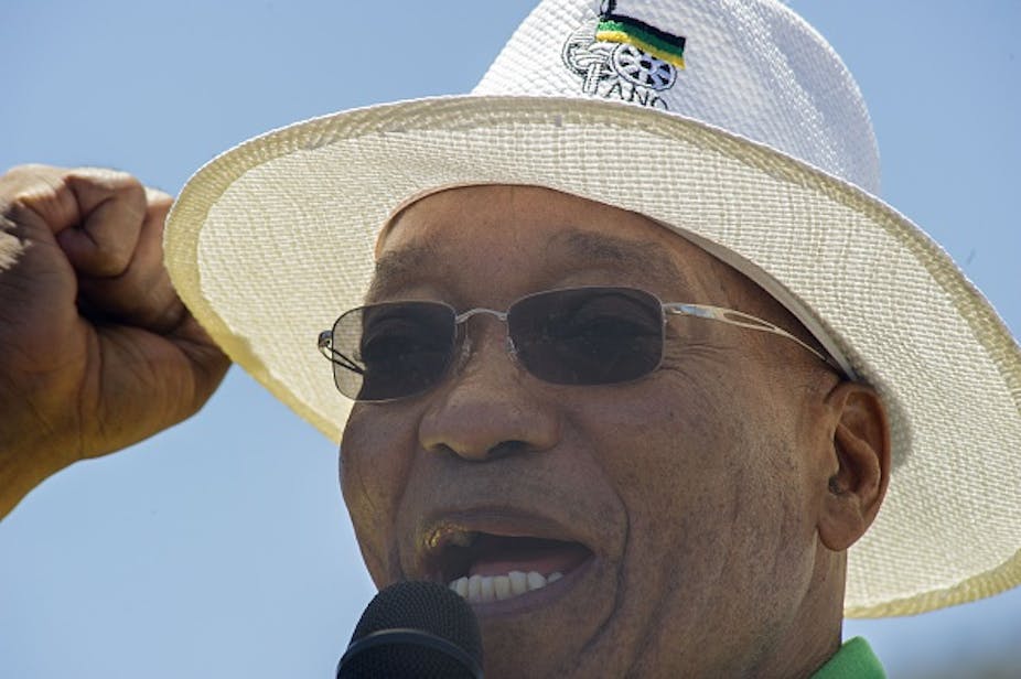 A man speaking intro a microphone, wearing a white hat with an ANC logo on it, and sunglasses