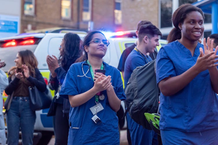 NHS workers gather in crowd and clap