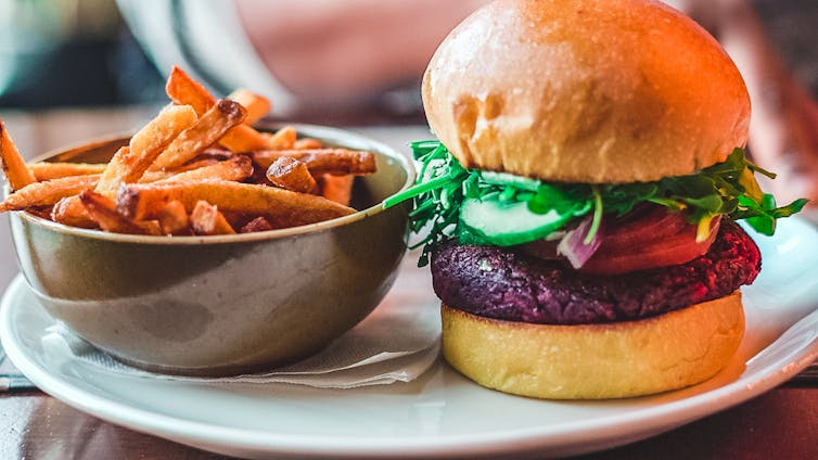 A vegan burger with a side of sweet potato fries.