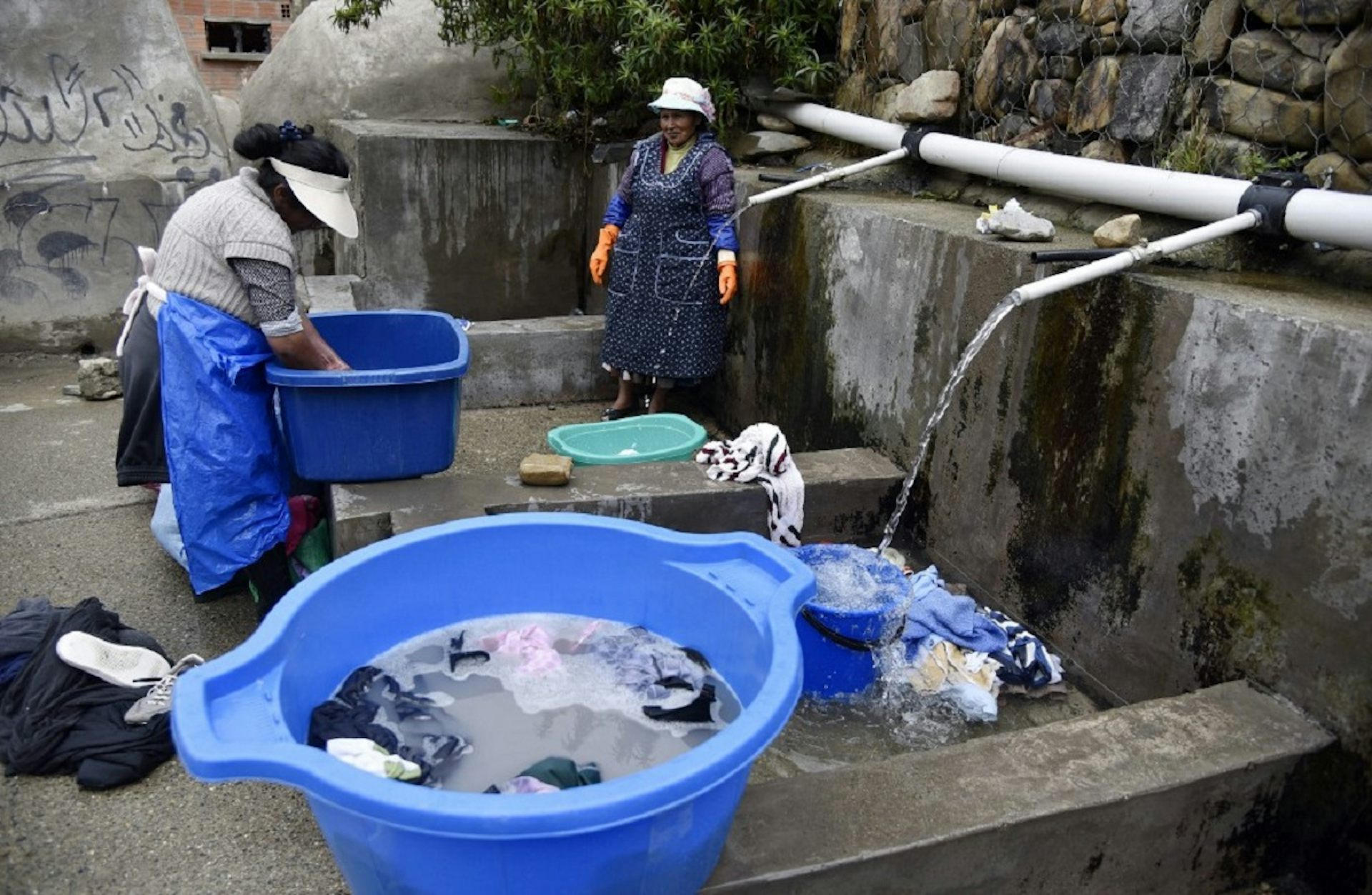 Deux femmes des peuples autochtones boliviens lavent leurs vêtements à un lavoir municipal utilisant de l'eau de pluie à La Paz, le 12 septembre 2019.