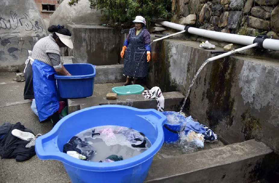 Deux femmes des peuples autochtones boliviens lavent leurs vêtements à un lavoir municipal utilisant de l'eau de pluie à La Paz, le 12 septembre 2019.