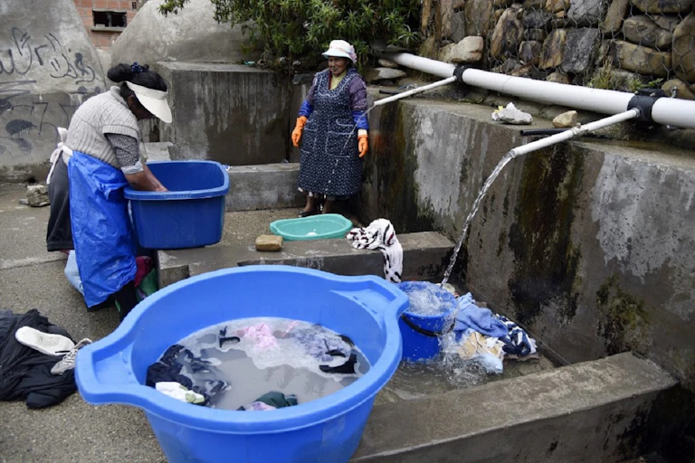 Deux femmes des peuples autochtones boliviens lavent leurs vêtements à un lavoir municipal utilisant de l'eau de pluie à La Paz, le 12 septembre 2019.