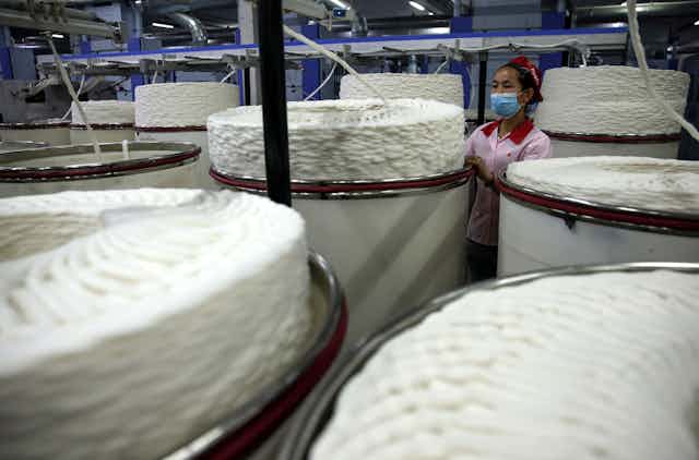 An ethnic minority worker operating machinery in a textile factory in Xinjiang