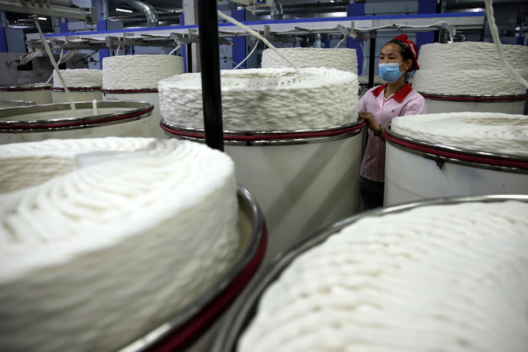 An ethnic minority worker operating machinery in a textile factory in Xinjiang