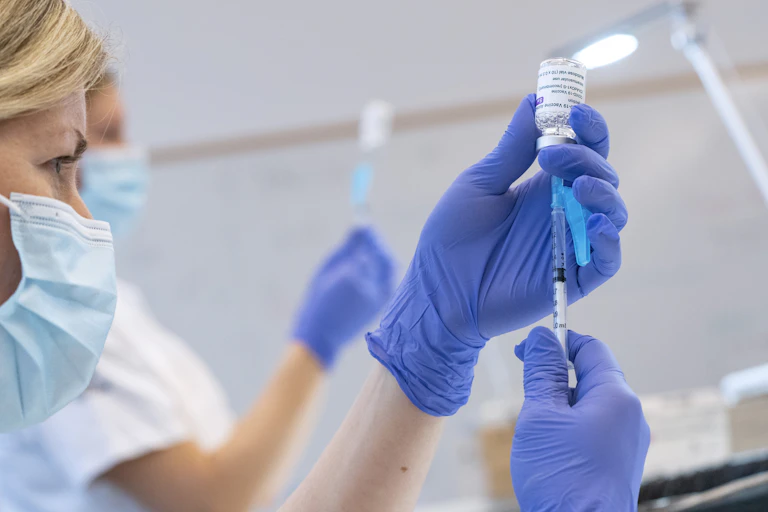 A nurse filling a syringe with COVID-19 vaccine