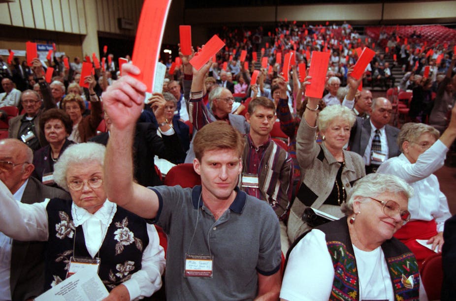 Voters raise their orange ballots to reject the Southern Baptist Convention's call for women to ``submit graciously'' to their husbands, during the Baptists General Convention of Texas held in El Paso, Texas. November 9,1999