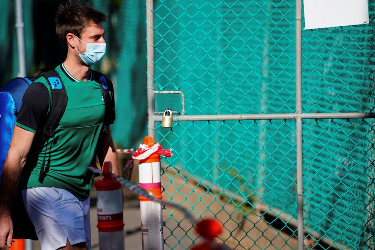 A tennis player undergoing mandatory quarantine enters a restricted training area in advance of the Australian Open in Melbourne, Australia