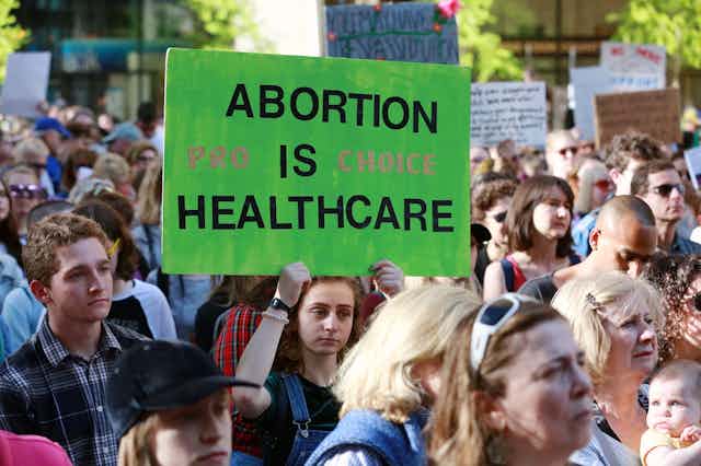 Protester holds up green sign in crowd that reads 'abortion is healthcare' 
