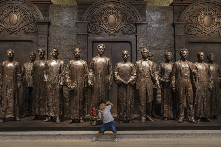 A young boy poses in front of 13 statues depicting the founders of the Chinese Communist Party in Shanghai, 1921.