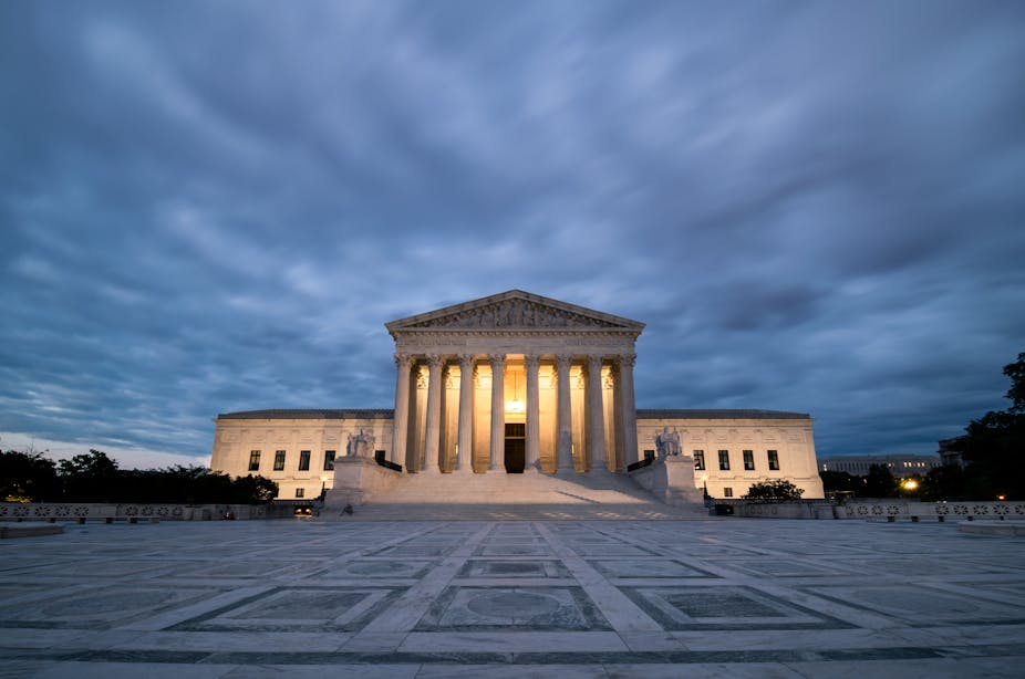 The supreme Court is lit up under an overcast sky.