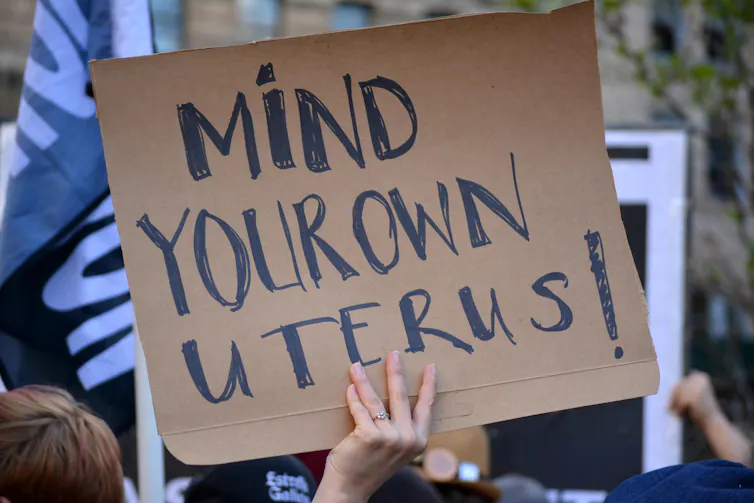 Protester holding up sign that says 'mind your own uterus!'