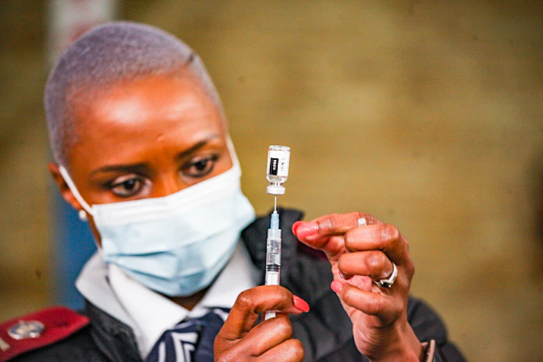 Woman in nurse's uniform and face mask holds syringe