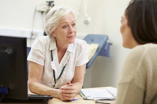 GP talks to patient in a consulting room.