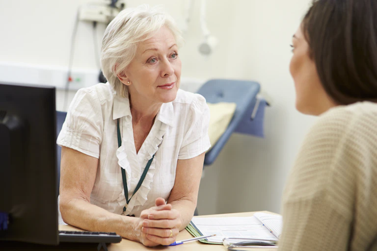 GP talks to patient in a consulting room.