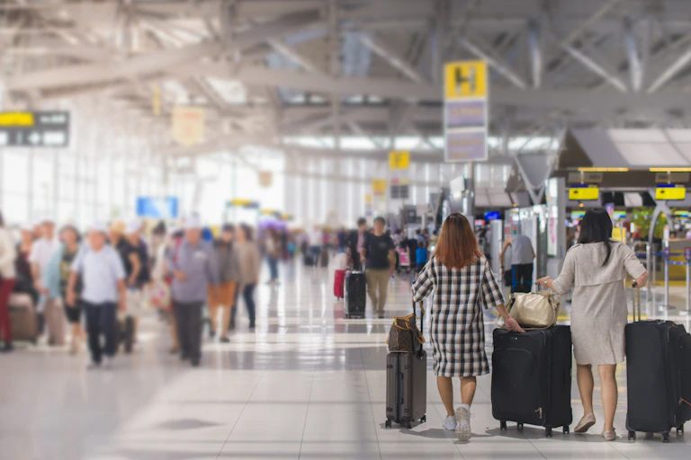 Two people push suitcases at an airport.