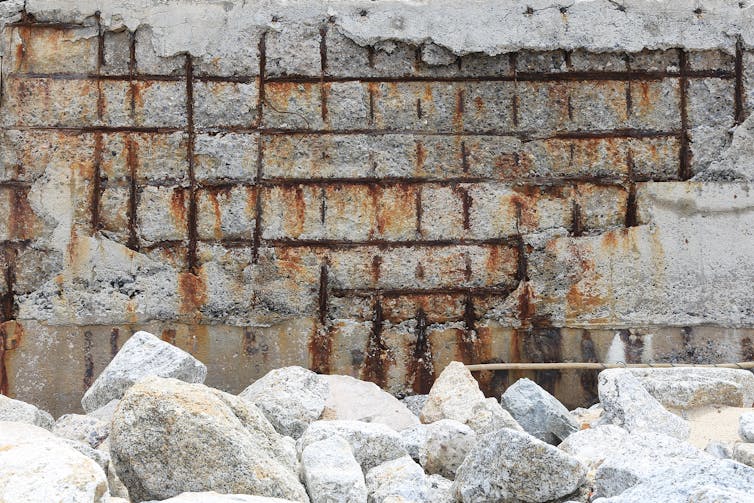 Crumbling reinforced concrete exposing rusted steel grid.