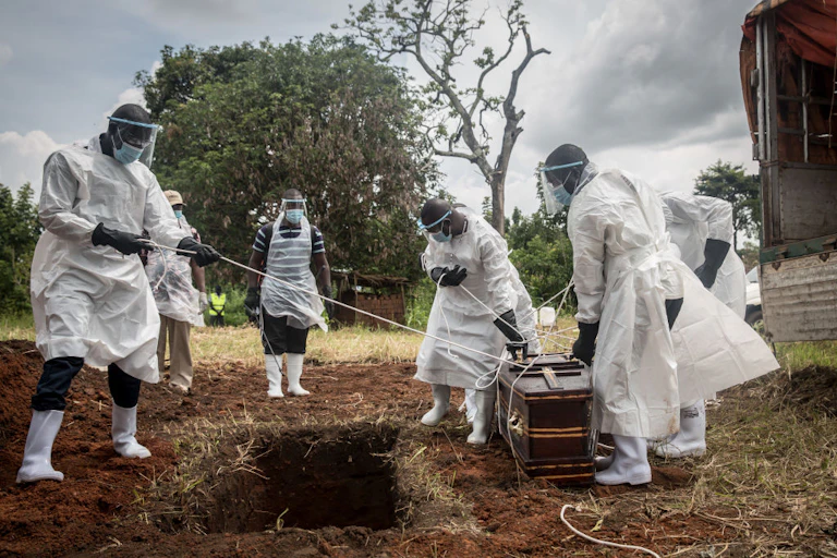 Health workers wearing protective suits lower the body of a COVID-19 victim for burial at a graveyard in Gulu, northern Uganda.