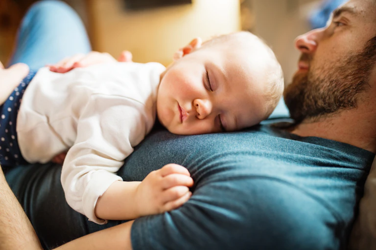 Un bébé endormi dans les bras d'un homme