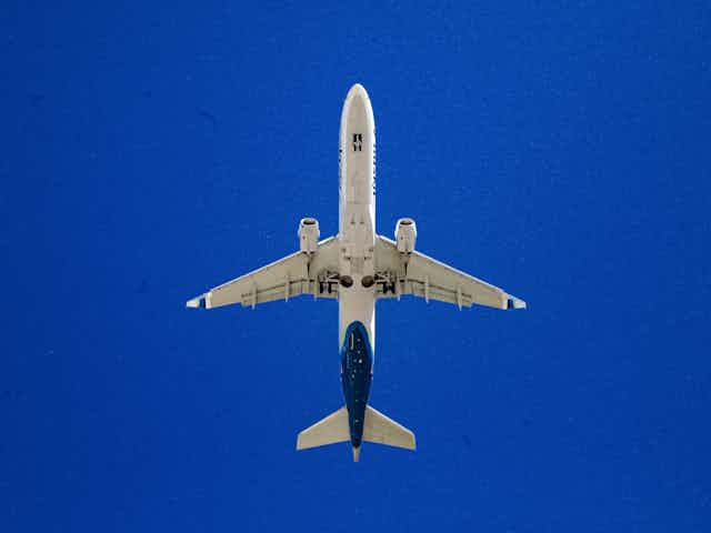 View of a passenger plane from below against a blue sky