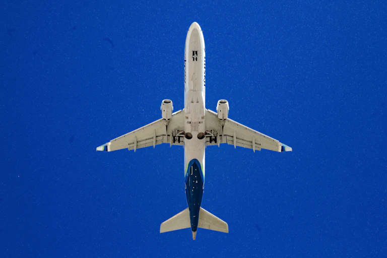 View of a passenger plane from below against a blue sky