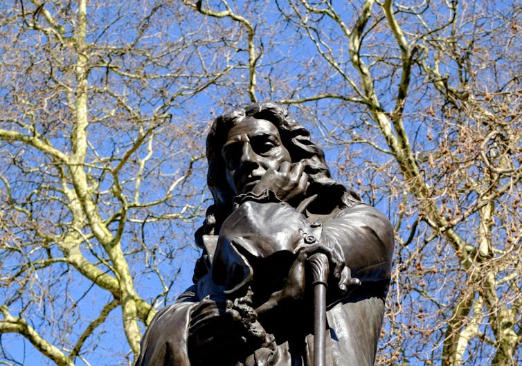 Top half of Edward Colston statue in Bristol centre with trees in background