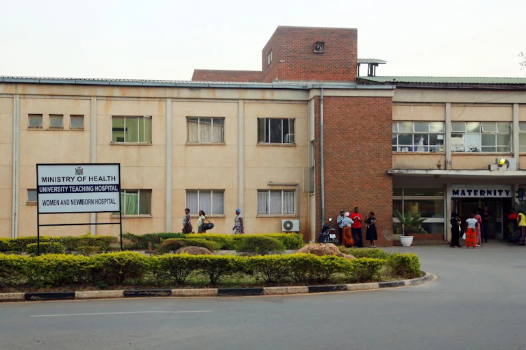 Outside of a hospital with a sign and people standing.