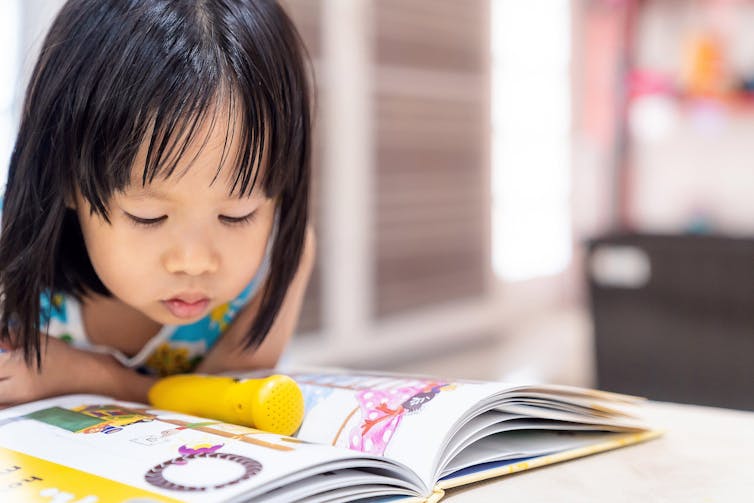 A young girl pores over an activity book