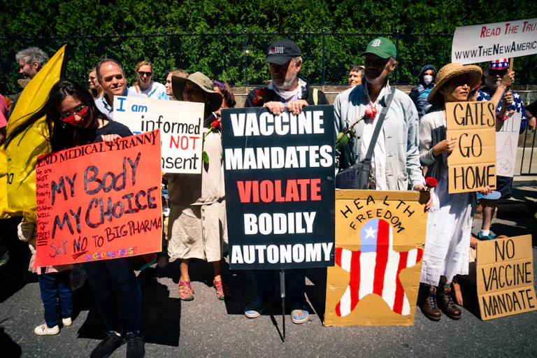 Anti-vaxxers hold signs reading 'my body my choice' 'vaccine mandates violate bodily autonomy'