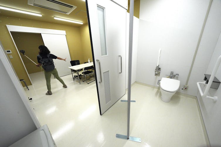 A sectioned-off room with white walls, a sliding door, and a urinal.