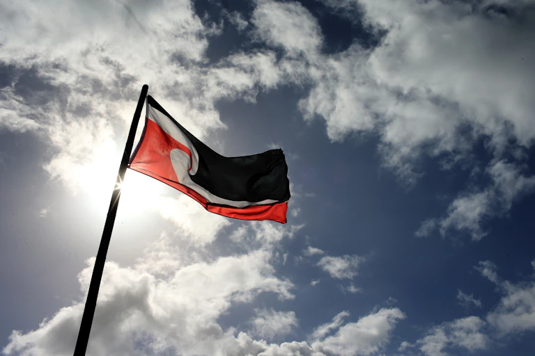 The Tino Rangatiratanga flag against a blue and cloudy sky