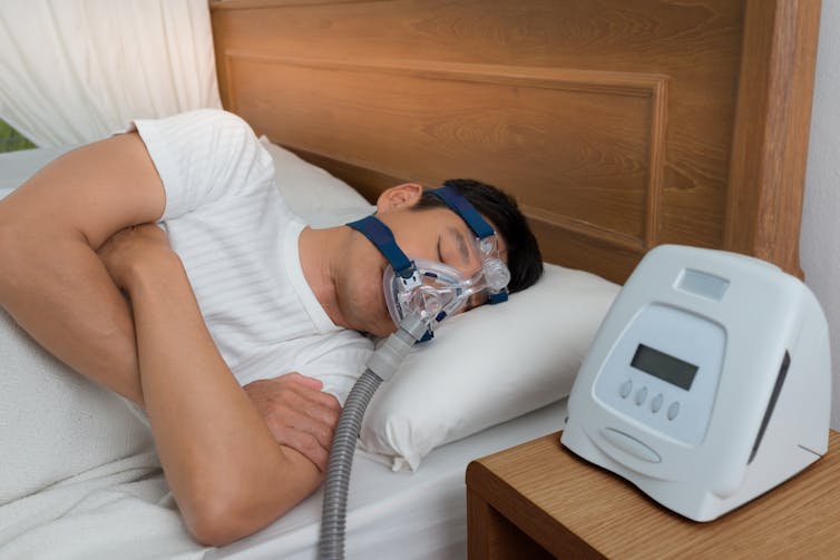 Man with CPAP machine sleeps in bed
