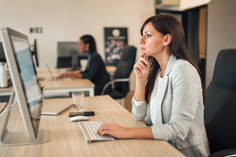 Woman in her 40s looks at her computer.