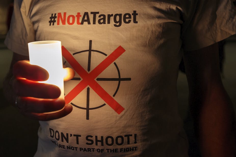 Person wearing a T-shirt with the slogan Not A Target holds a candle or torch