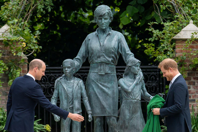 Princes William and Harry stand in front of a statue to their mother, Diana, Princess of Wales.