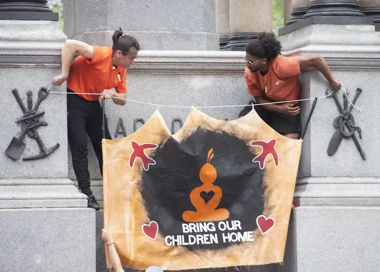 People hang a banner that says 'bring our children home'