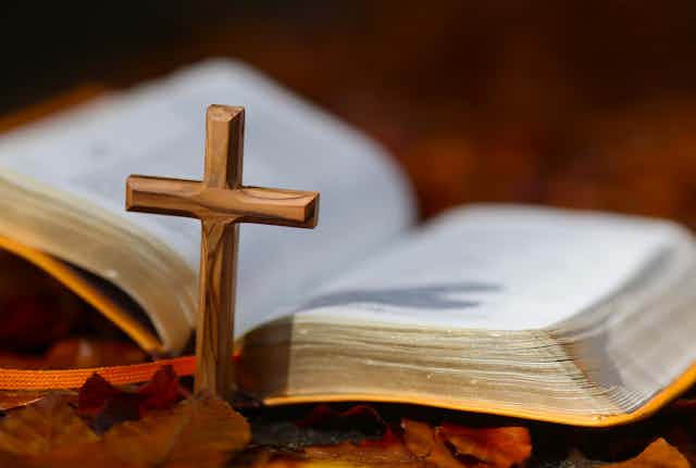 An open Bible placed alongside a Christian cross