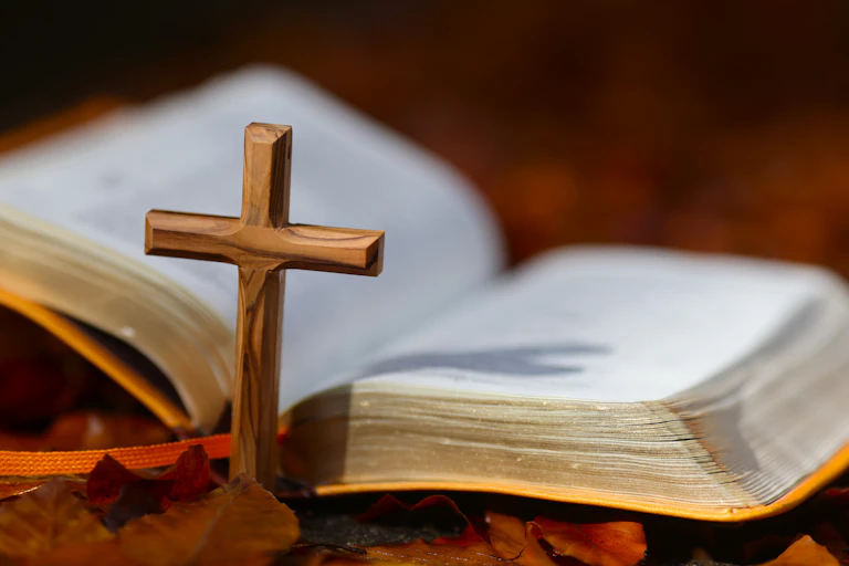 An open Bible placed alongside a Christian cross