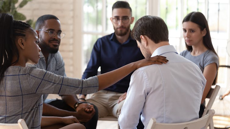 A group of people support a grieving man