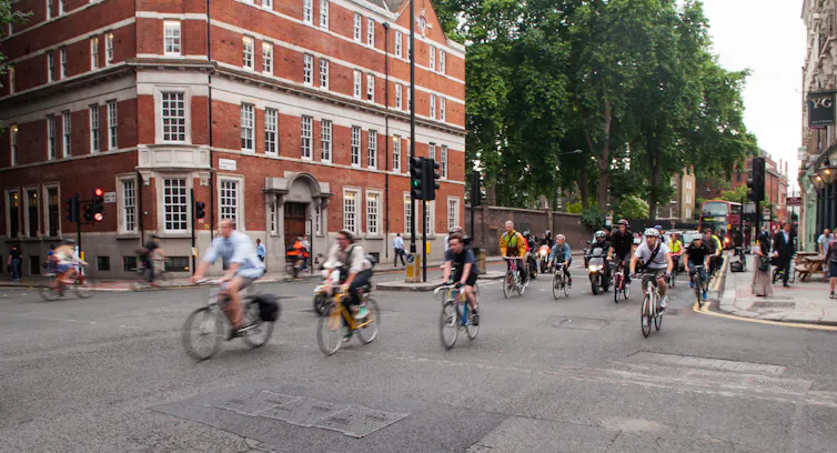 Commuter cyclists set off from a green light at a busy road junction in Central London